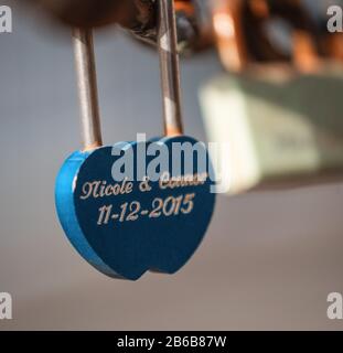 Closeup of a padlock hanging on chain link of the bridge / Fence Stock Photo