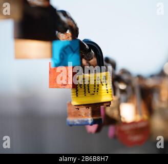 Closeup of a padlock hanging on chain link of the bridge / Fence Stock Photo