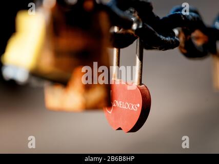 Closeup of a padlock hanging on chain link of the bridge / Fence Stock Photo