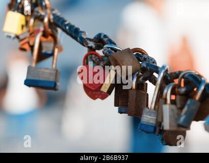 Closeup of a padlock hanging on chain link of the bridge / Fence Stock Photo
