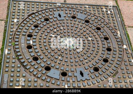 Manhole cover walled in cobblestones on the street Stock Photo