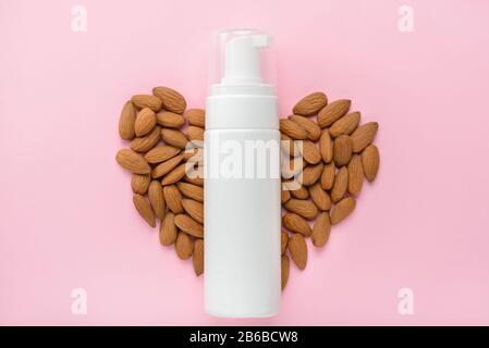 Nourishing gel rich in vitamin b concept. Top above overhead view photo of bottle with foam and nuts in shape of heart isolated pastel background empt