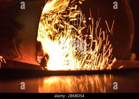 spark explosion from pouring coals into grill on dark evening Stock Photo