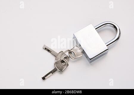 Locked silver lock with three keys on a white background. Stock Photo