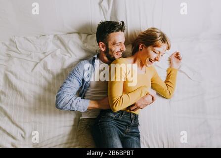 Two young adults at home - Beautiful happy couple of lovers having fun in bed Stock Photo