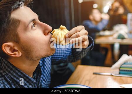 Man eating in georgian restaurant national snack Khinkali, that is a relative to dumplings and raviolli Stock Photo