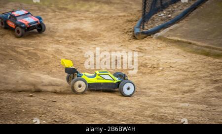 Yellow electric RC buggy racing on an offroad outdoor track Stock Photo