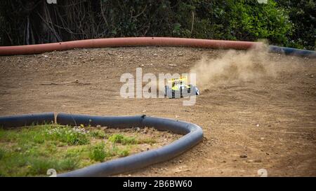 Yellow electric RC buggy racing on an offroad outdoor track Stock Photo