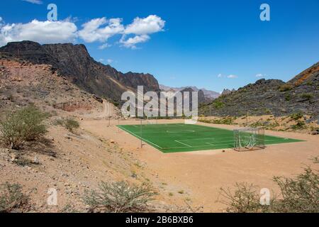 Football and Soccer field inside Mountain and valley along Wadi Sahtan road in Al Hajir mountains between Nizwa and Mascat in Oman Stock Photo