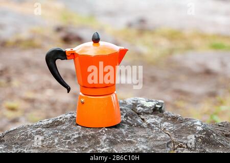 Coffeepot with hot coffee standing on a rocky cliff outdoors. Hiking and camping kitchen utensils and gear concept Stock Photo