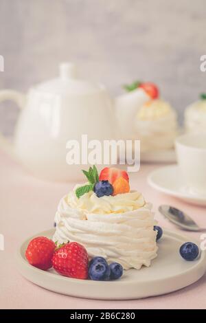 Pavlova meringue cake with fresh berries on pink background, toned vintage Stock Photo