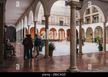 Seville, Spain - January 17, 2020: Courtyard of University of Seville, one of the top-ranked universities in Spain, group of people talking inside. Se Stock Photo
