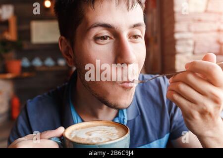Young man enjoying coffee with piece of cake in cafe Stock Photo