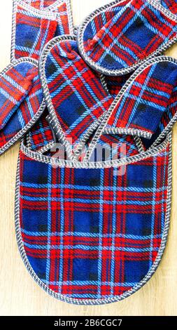 A lot of colorful comfortable, cushioned, checkered disposable slippers are on the wooden floor. Vertical. Top view. Concept of hospitality. Close-up. Stock Photo