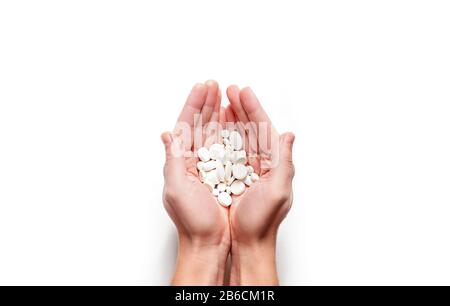 Man hands with handful of white pills isolated on white background. Copy space. Stock Photo