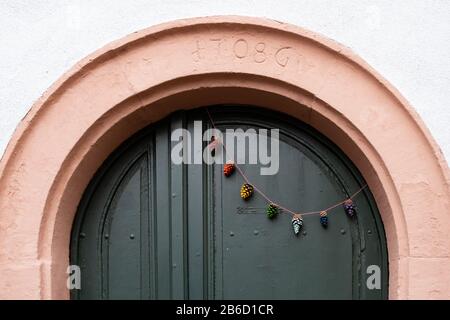 Painted pine cone garland hanging on door - Heidelberg, Germany Stock Photo