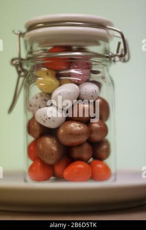 Glass jar full of mini chocolate easter eggs. 09/03/2020. droitwich, worcester, england, uk. Glass jar full of mini chocolate easter eggs. sat on a pl Stock Photo