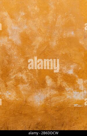 Texture of an old orange plastered street wall. old wall with peeling paint, scratched stained plaster. Stock Photo
