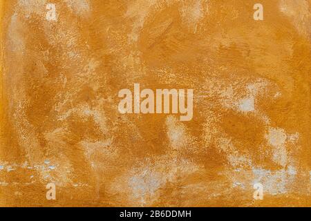 Texture of an old orange plastered street wall. old wall with peeling paint, scratched stained plaster. Stock Photo