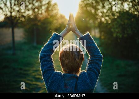 Young woman in park welcomes sunshine Stock Photo