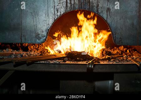 blacksmith furnace inner space with burning fire and metal blanks heating up in it Stock Photo