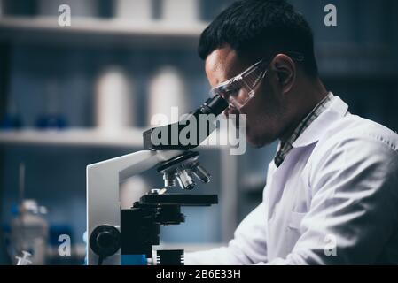 Young scientist working with a microscope in a laboratory. Young scientist doing some research. Stock Photo