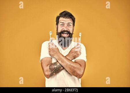 Get rid of plaque and tartar. Happy hipster hold toothbrushes. Bearded man smile with tooth brushes. Dental health. Teeth and gums health. Healthy mouth. Oral health care. Teeth affect your health. Stock Photo