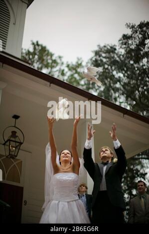 Young adult bride and groom releasing doves on their wedding day. Stock Photo