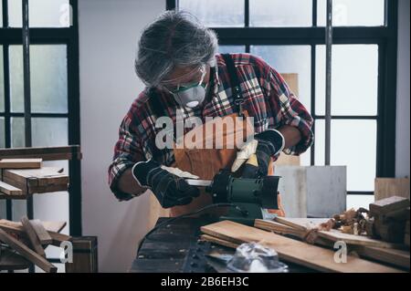 old carpenter man working in carpenter studio Stock Photo