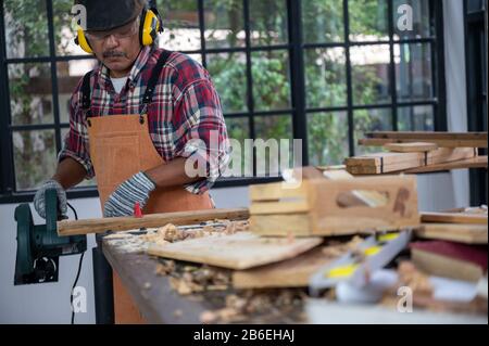 Carpenter working on woodworking machines in carpentry shop, wooden product Stock Photo