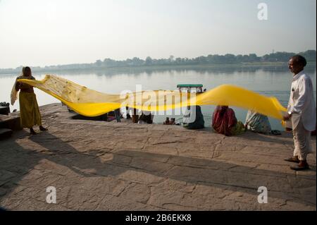 Couple shaking sari to dry it after woman bathed in the Narmada River, Maheshwar, Khargone District, Madhya Pradesh, India Stock Photo