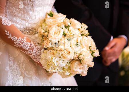 Beautiful bridal wedding bouquet isolated in hands with blurred groom together Stock Photo