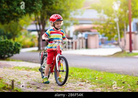 Kids on bike in park. Children going to school wearing safe bicycle helmets. Little boy biking on sunny summer day. Active healthy outdoor sport for y Stock Photo