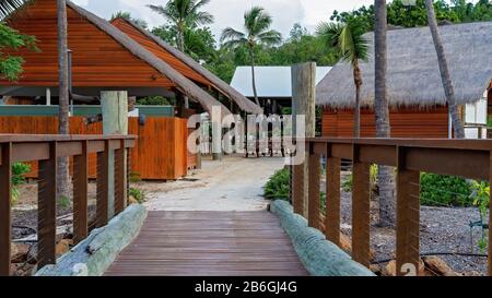A timber boardwalk entry into a tropical resort in landscaped gardens with restaurant facilities Stock Photo