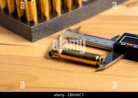 Production of cartridges for a rifle, reload. Measurement of the empty cartridges with a caliper. Close up Stock Photo