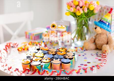 Cupcakes for kids birthday celebration. Jungle animals theme children party. Decorated room for boy or girl kid birthday. Table setting with presents, Stock Photo