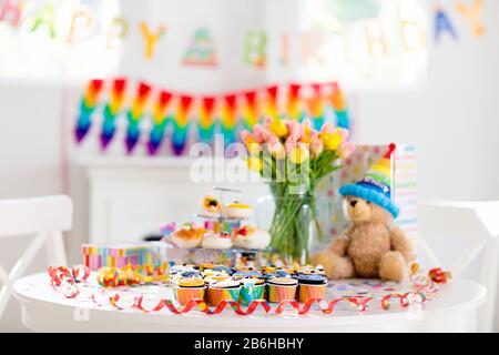 Cupcakes for kids birthday celebration. Jungle animals theme children party. Decorated room for boy or girl kid birthday. Table setting with presents, Stock Photo