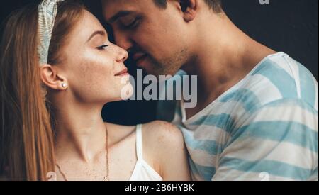 Close up portrait of a caucasian lady with red hair and freckles embraced by her lover posing cheerfully Stock Photo
