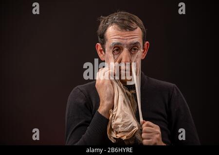 the man will take off the mask of the old man and turn into a young man Stock Photo