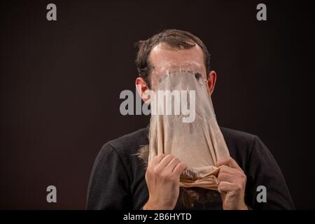 the man will take off the mask of the old man and turn into a young man Stock Photo
