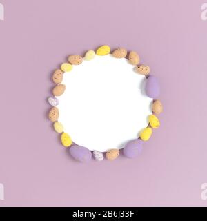 Round frame made of easter colorful eggs on a purple background. Holiday concept. Stock Photo