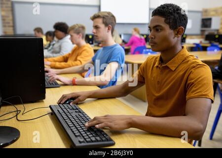Side view of students working on computers Stock Photo