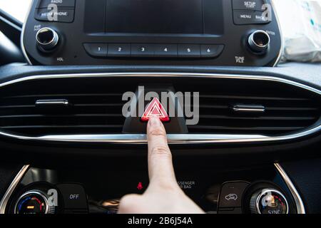 Finger pressing a hazard warning lights button on a modern luxury korean car Stock Photo