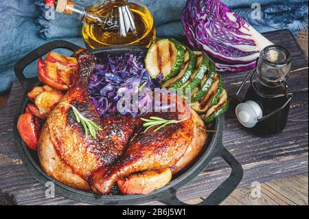 Fried pickled duck legs with a side dish of vegetables . Grilled zucchini, red cabbage and spices on a wooden table. Stock Photo