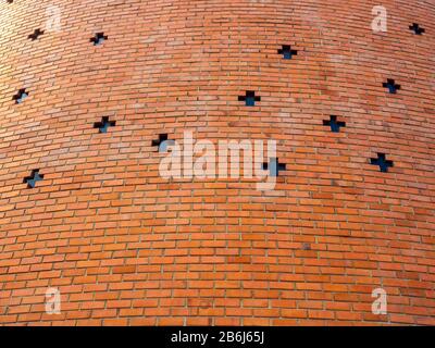 Red brick wall background with cross shaped window. Seamless brick wall texture building. Stock Photo