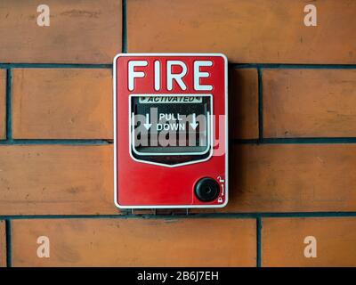 Red manual pull fire alarm safety system. Close-up pull station or call point, manual fire alarm activation on brick wall background. Stock Photo