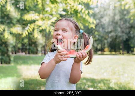 Funny baby eating watermelon outdoors in the park Stock Photo