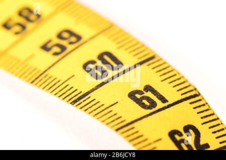 Close-up of a yellow measuring tape isolated on white - 61 - Selective focus Stock Photo