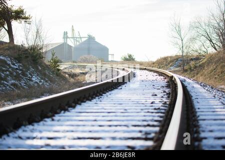 Sun reflecting on railroad rail in winter with snow background Stock Photo