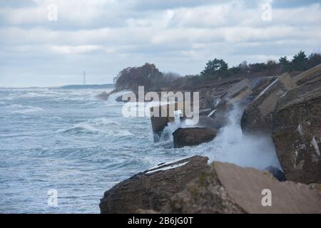 Waves crashing against breakwater consisting of gray concrete tetrapods. Liepaja, Latvia. Stock Photo